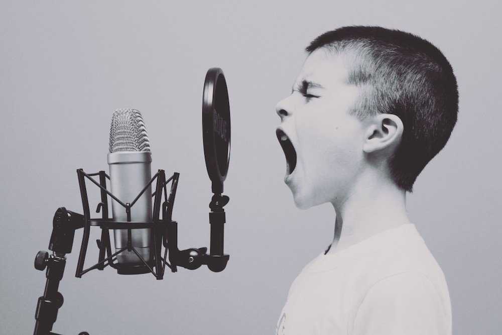 Enfant chantant à tue-tête dans un microphone de studio