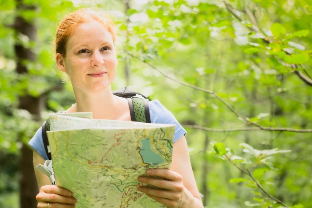Jeune fille dans la forêt, s'orientant avec une carte de randonnée