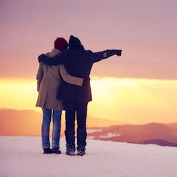 Un couple sur une montagne enneigée regarde au loin, 